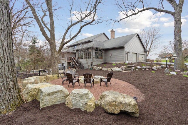 2555 W Deer Path Trl, Janesville, WI 53545 - back of property with a fire pit, a chimney, a wooden deck, an attached garage, and stairway