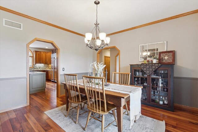 2555 W Deer Path Trl, Janesville, WI 53545 - dining space featuring crown molding, hardwood / wood-style floors, arched walkways, a notable chandelier, and visible vents
