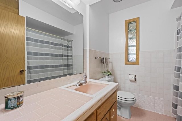 bathroom featuring vanity, toilet, tile walls, a wainscoted wall, and tile patterned floors