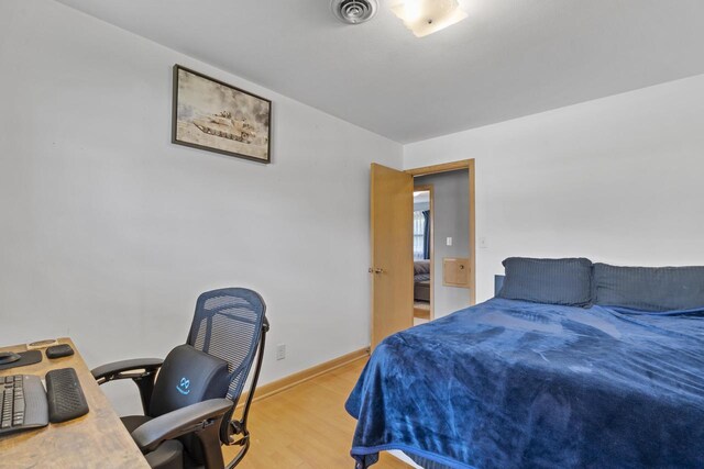 bedroom featuring baseboards, light wood-style flooring, and visible vents