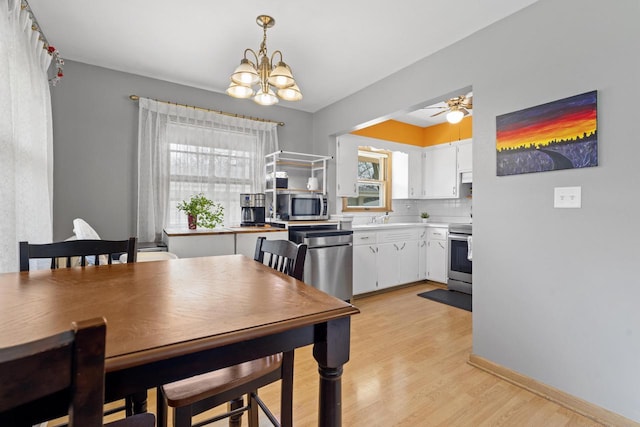 dining room featuring plenty of natural light, ceiling fan with notable chandelier, and light wood-type flooring