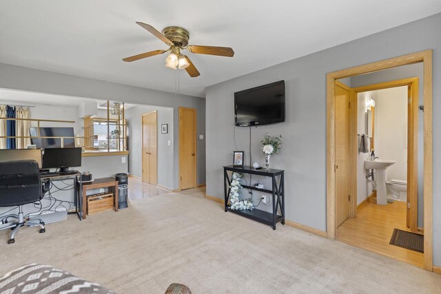 home office with ceiling fan, a sink, baseboards, and carpet