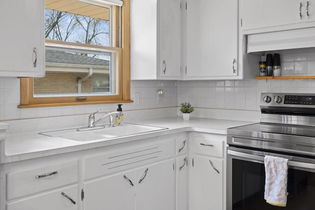 kitchen with stainless steel electric stove, ventilation hood, a sink, and white cabinets