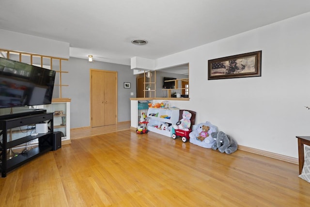 living area with baseboards, visible vents, and wood finished floors