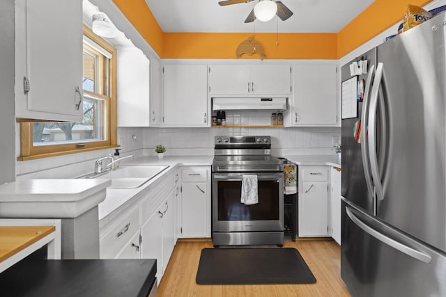kitchen with a sink, light wood-style floors, under cabinet range hood, a ceiling fan, and appliances with stainless steel finishes