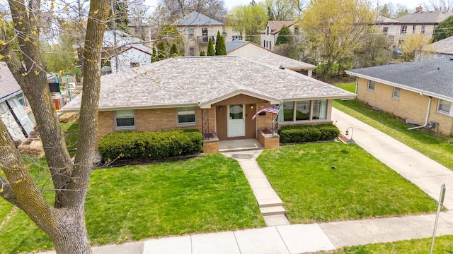 ranch-style house featuring brick siding, a shingled roof, a front lawn, and a residential view