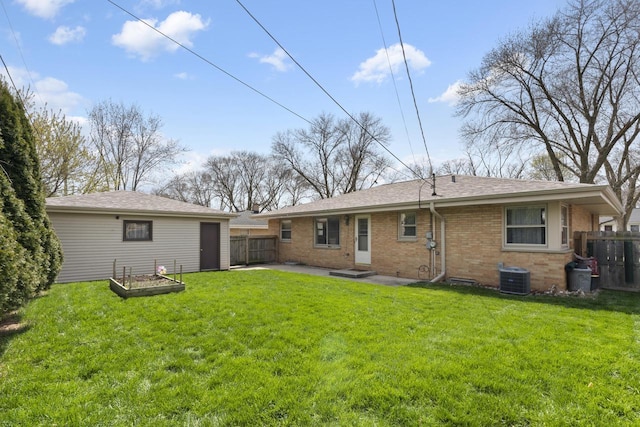rear view of house with brick siding, central AC unit, a lawn, and fence