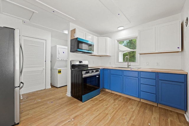 W160N9696 Colonial Dr, Germantown, WI 53022 - kitchen featuring appliances with stainless steel finishes, a sink, blue cabinets, estacked washer and dryer, and light wood-style flooring