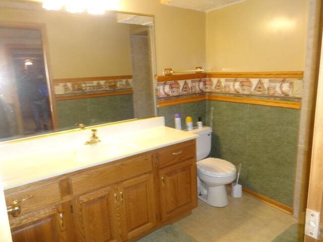 545 Skyhawk Ave, Campbellsport, WI 53010 - bathroom featuring tile walls, wainscoting, vanity, tile patterned floors, and toilet