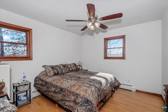 W7604 Sleepy Eye Rd, Minong, WI 54859 - bedroom with a baseboard heating unit, baseboards, light wood-style floors, and ceiling fan