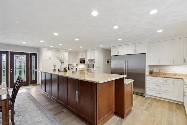 4441 N John Paul Rd, Milton, WI 53546 - kitchen featuring appliances with stainless steel finishes, white cabinetry, light wood finished floors, and a center island