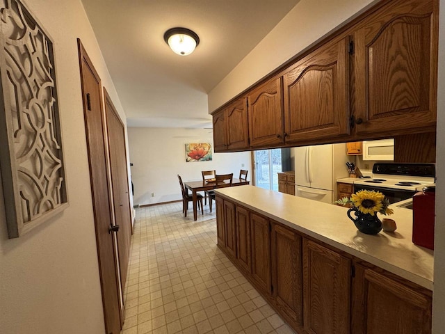 kitchen featuring light countertops, baseboards, electric range, a peninsula, and freestanding refrigerator