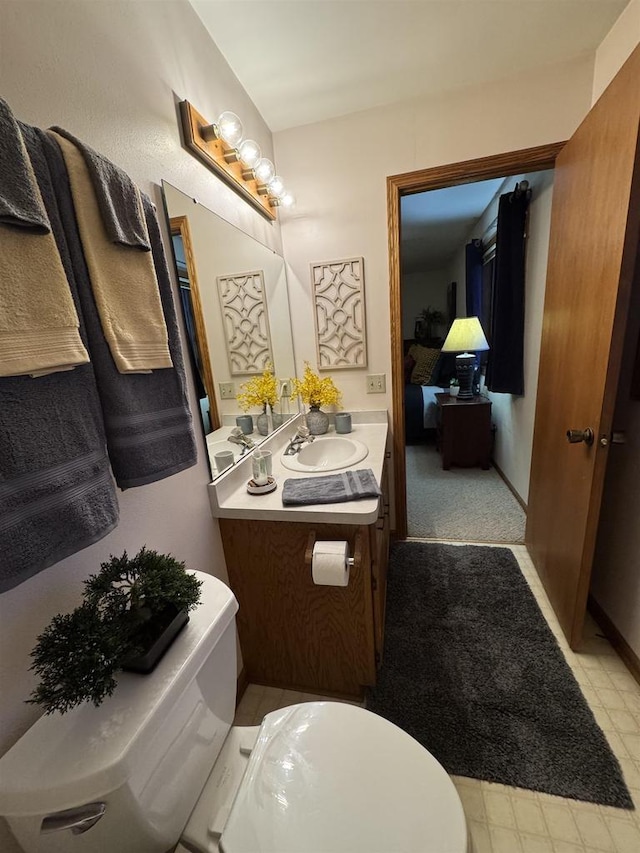 ensuite bathroom with toilet, vanity, and connected bathroom
