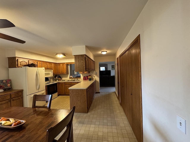 kitchen featuring a ceiling fan, brown cabinets, white appliances, light countertops, and a peninsula