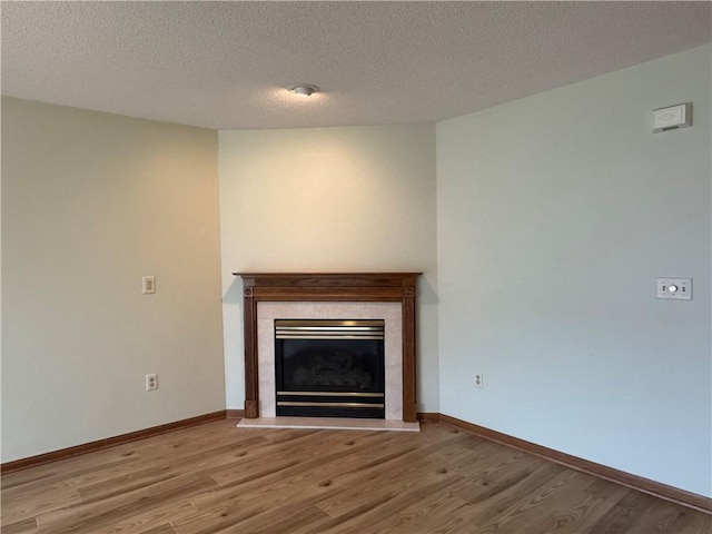 1140 W Hamilton Ave Unit 1140, Eau Claire, WI 54701 - unfurnished living room with a glass covered fireplace, wood finished floors, a textured ceiling, and baseboards
