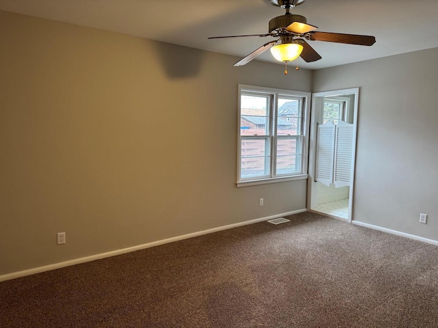 empty room with baseboards, dark colored carpet, visible vents, and ceiling fan