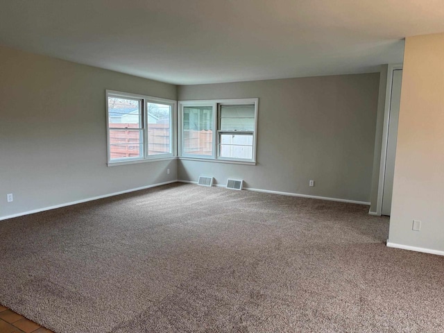 carpeted empty room featuring baseboards and visible vents