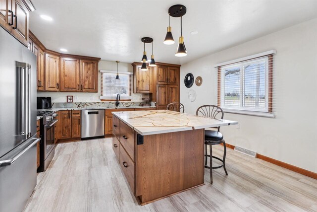 W5184 Shady Ln, Shawano, WI 54166 - kitchen featuring a breakfast bar, light wood-style floors, light stone countertops, a center island, and appliances with stainless steel finishes