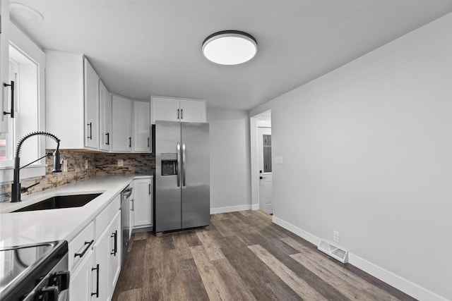 N5599 Mill St, Shiocton, WI 54170 - kitchen with stainless steel appliances, a sink, dark wood-style flooring, backsplash, and white cabinetry