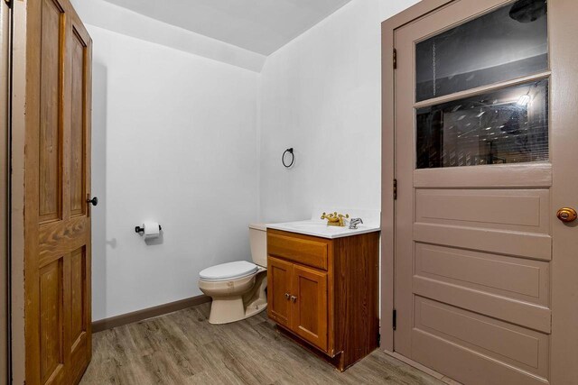 N2226 State Road 57, New Holstein, WI 53061 - bathroom featuring vanity, baseboards, wood finished floors, and toilet