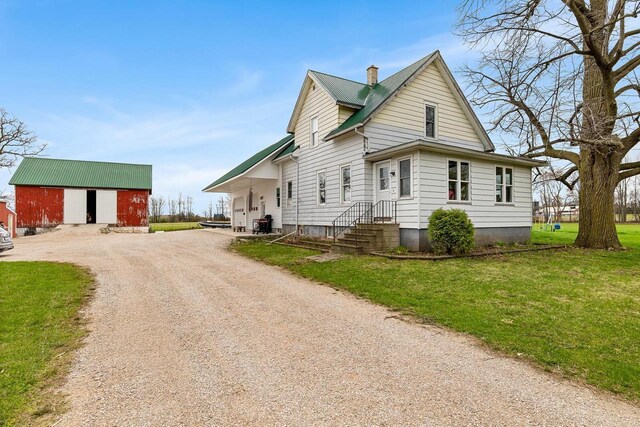 N2226 State Road 57, New Holstein, WI 53061 - view of front of property featuring an outdoor structure, a front yard, a chimney, metal roof, and driveway