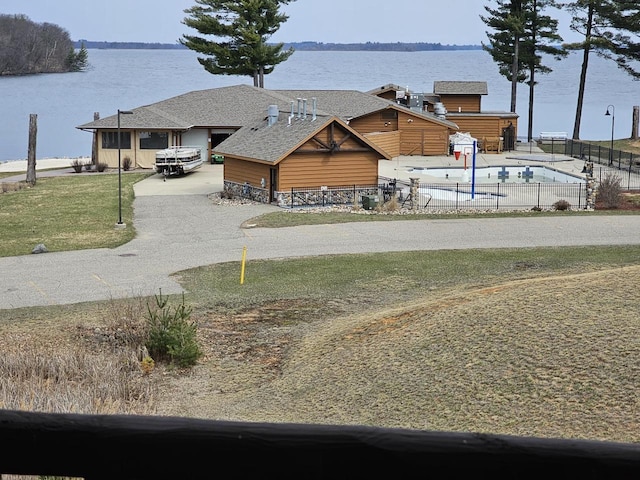 exterior space featuring fence, a water view, and driveway