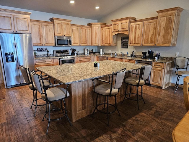 kitchen featuring dark wood-style floors, stainless steel appliances, vaulted ceiling, light stone countertops, and a center island