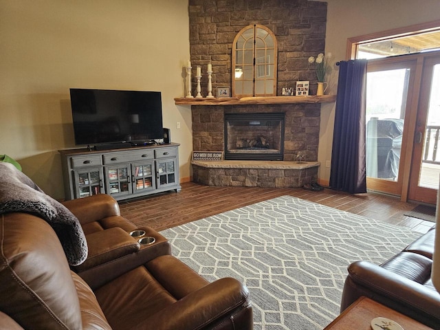 living room with baseboards, wood finished floors, and a stone fireplace