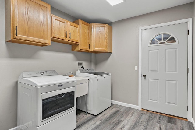 W9517 Parkway Dr, Poynette, WI 53955 - laundry room featuring independent washer and dryer, light wood-style flooring, a sink, baseboards, and cabinet space