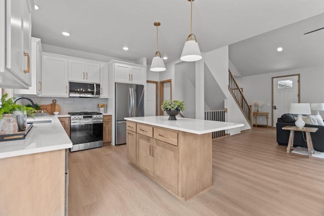 3216 Eclipse Dr, Green Bay, WI 54311 - kitchen with stainless steel appliances, light wood finished floors, backsplash, a kitchen island, and light countertops