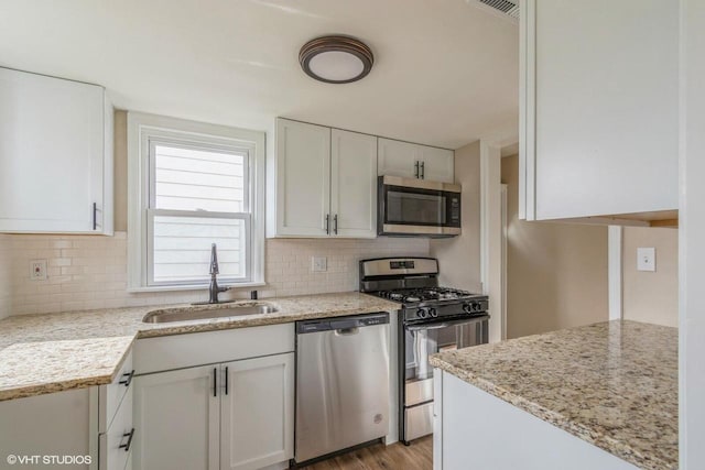 4858 N 73rd St, Milwaukee, WI 53218 - kitchen featuring white cabinets, light stone counters, a sink, tasteful backsplash, and appliances with stainless steel finishes