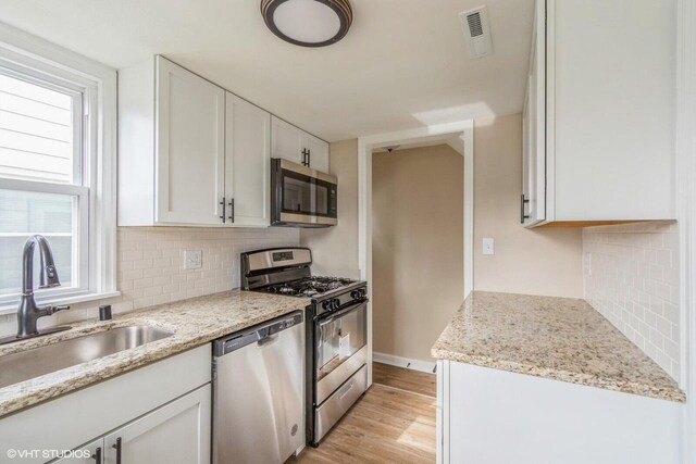 4858 N 73rd St, Milwaukee, WI 53218 - kitchen with white cabinets, stainless steel appliances, decorative backsplash, and a sink