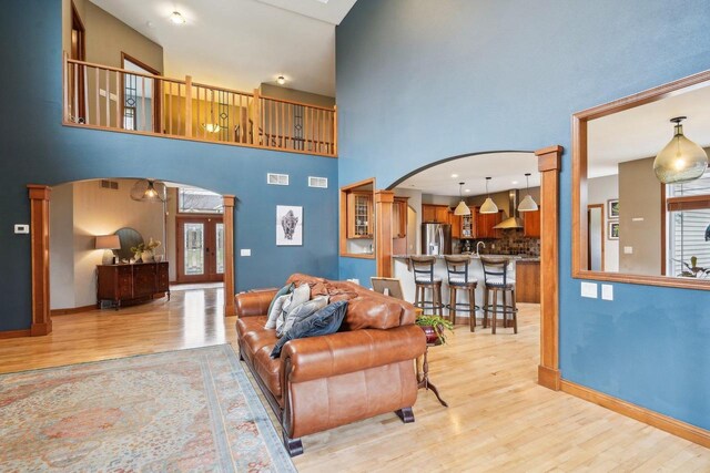 1310 Hanover Ct, Waunakee, WI 53597 - living area featuring arched walkways, light wood-style flooring, a high ceiling, and ornate columns