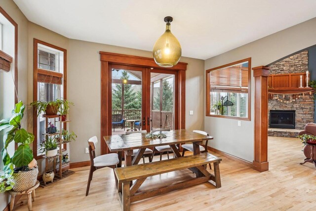 1310 Hanover Ct, Waunakee, WI 53597 - dining space featuring a stone fireplace, baseboards, light wood-style floors, and a healthy amount of sunlight