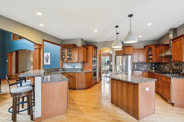 1310 Hanover Ct, Waunakee, WI 53597 - kitchen featuring arched walkways, brown cabinets, a breakfast bar area, and stainless steel appliances