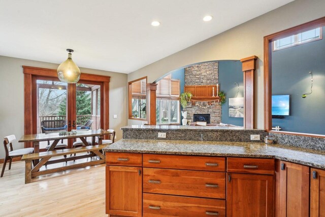 1310 Hanover Ct, Waunakee, WI 53597 - kitchen with arched walkways, light wood-style flooring, hanging light fixtures, and light stone counters