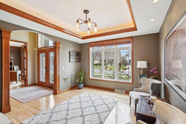 1310 Hanover Ct, Waunakee, WI 53597 - foyer with arched walkways, visible vents, a chandelier, ornate columns, and wood finished floors
