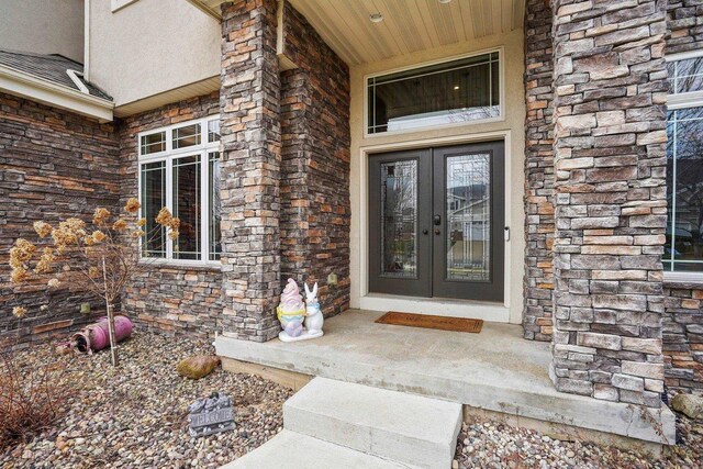 1310 Hanover Ct, Waunakee, WI 53597 - view of exterior entry featuring stone siding, covered porch, french doors, and stucco siding