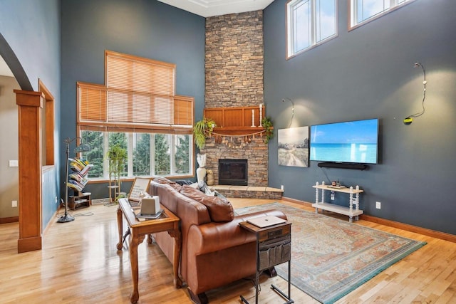 1310 Hanover Ct, Waunakee, WI 53597 - living area featuring arched walkways, baseboards, a towering ceiling, light wood-style floors, and a fireplace