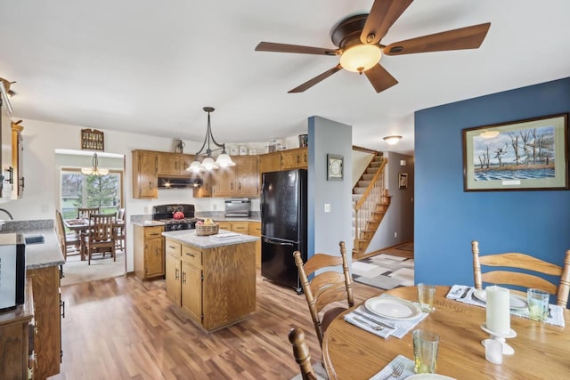 kitchen featuring a center island, ceiling fan, light countertops, under cabinet range hood, and black appliances