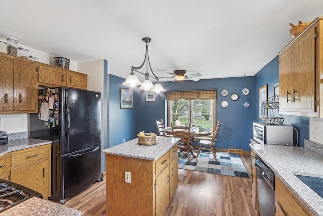 kitchen featuring wood finished floors, ceiling fan, decorative light fixtures, a kitchen island, and appliances with stainless steel finishes