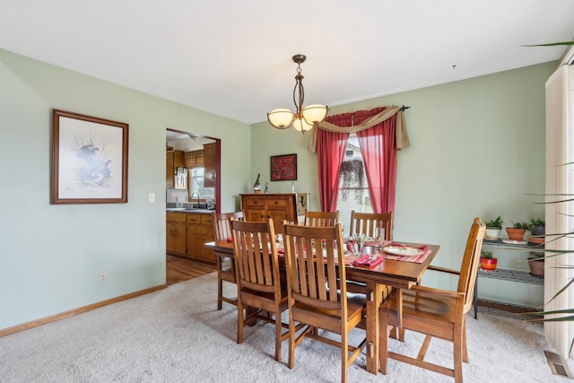 dining space with baseboards and light colored carpet