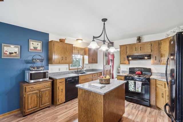 kitchen featuring brown cabinets, under cabinet range hood, a sink, light wood-type flooring, and black appliances