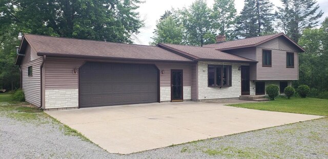3821 90th St N, Wisconsin Rapids, WI 54494 - split level home featuring a chimney, a shingled roof, an attached garage, driveway, and stone siding