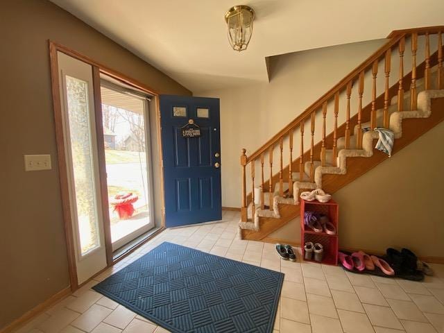 entrance foyer featuring tile patterned flooring, baseboards, and stairway