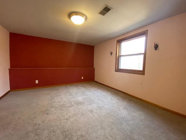 empty room with baseboards, carpet flooring, and visible vents