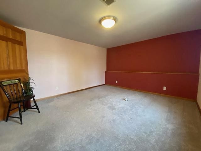empty room with baseboards, visible vents, and light carpet