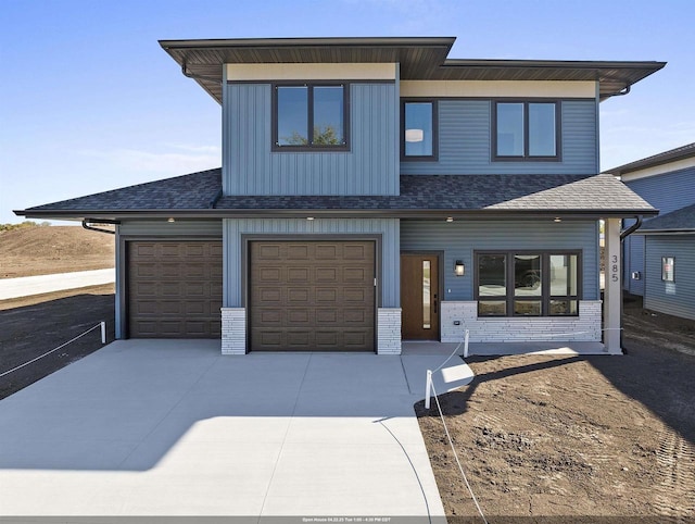 view of front of house with brick siding, a shingled roof, and concrete driveway
