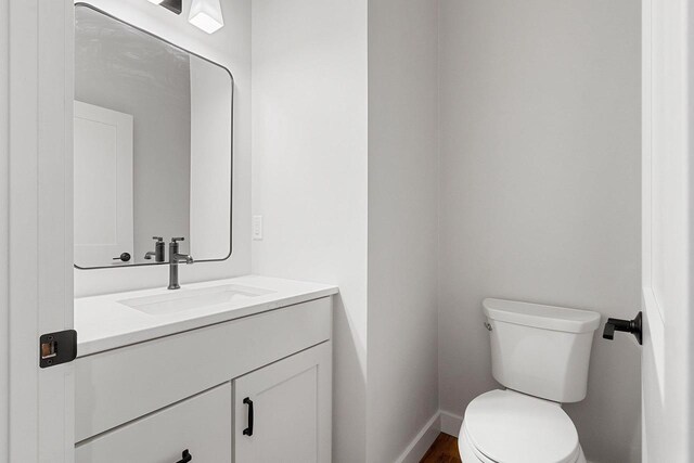 bathroom featuring baseboards, toilet, and vanity