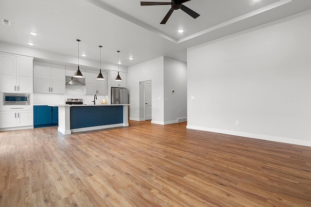 unfurnished living room with ceiling fan, baseboards, light wood-type flooring, and recessed lighting